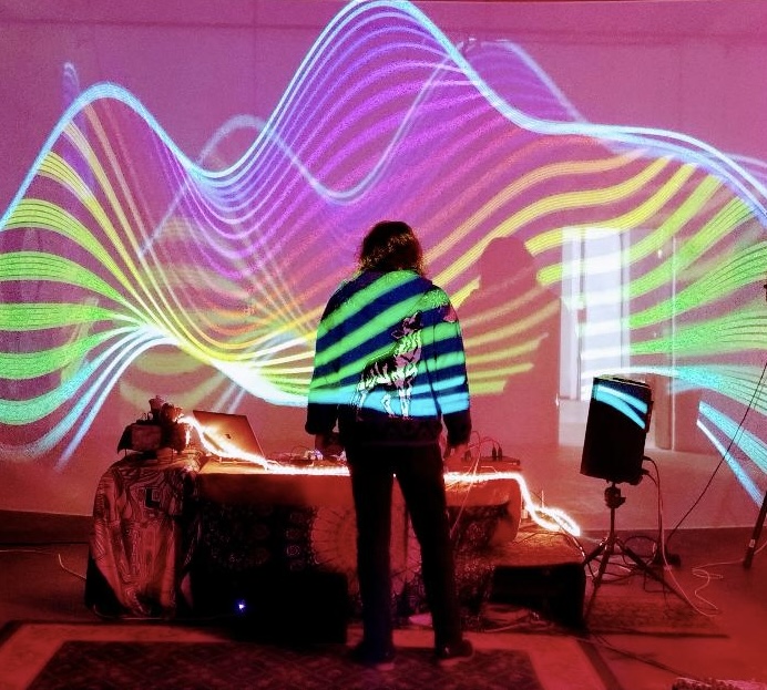 DaWei DJing in front of a wall of psychedelic laser light